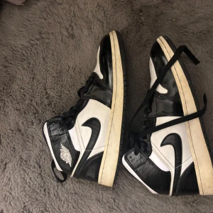 Svartvita Nike Air Jordans - Säljer ett par klassiska svartvita Nike Air Jordans med hög snörning och logga på sidan. storlek 38,5 köpta på merchsweden.