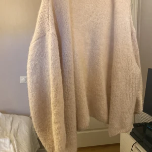 Beige stickad kofta från Lindex - Mysig beige stickad kofta från Lindex. Perfekt för kyliga dagar med sin lösa passform och långa ärmar. Koftan är tillverkad i ett mjukt material som ger en skön känsla. Ett måste i garderoben för en stilren look.