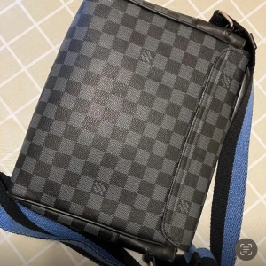 Luis Vuitton distrikt - Snygg axelväska med klassiskt rutigt mönster i svart och grått. Väskan har en justerbar axelrem i svart och blått, perfekt för vardagsbruk. Den är stilren och passar till många olika outfits.