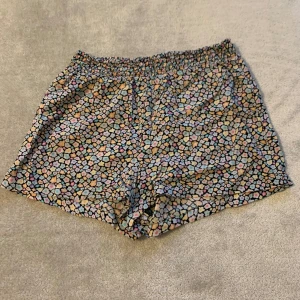 Mönstrade shorts med stenar - Säljer ett par coola shorts med ett unikt blom mönster i olika färger. De har en elastisk midja för extra komfort. Perfekta för en avslappnad dag i solen!