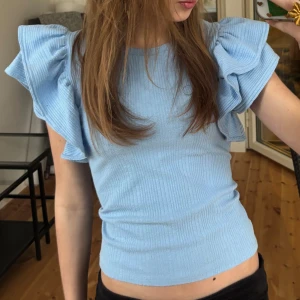 Blå topp - Snygg ljusblå ribbad topp från Zara med volangdetaljer på axlarna. Superfin till sommaren💕Pris kan diskuteras!