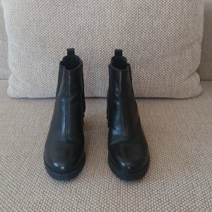 Svarta boots med klack - Snygga svarta boots i skinn med klack och dragkedja på sidan. Perfekta för en stilren look. De har en rund tå och en robust sula för extra komfort.