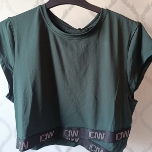 Grön croppad topp från ICANIWILL - Snygg grön croppad topp från ICANIWILL med elastiskt band med logotypen i nederkant. Aldrig använd! Pris kan diskuteras!!! 