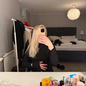 Svart långärmad topp - Säljer en stilren svart långärmad topp med en tight passform. Perfekt för en elegant look. Toppen har en enkel design som gör den lätt att matcha med olika outfits. Även en slit på denna på armen 