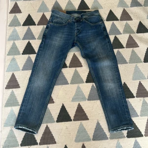 Dondup George  - Snygga blå jeansbyxor med en klassisk femficksdesign och knappgylf. De har en lätt tvättad look och raka ben. Perfekta för en avslappnad stil.