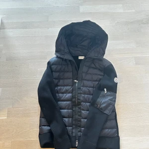  Moncler cardigan  - Säljer min Moncler cardigan som är nästan ny. Använt 1 gång. Den scannar pă logan och insida taggen. S/M. Snygg svart jacka från Moncler med huva och dragkedja. Jackan har en quiltad design på framsidan och ärmarna är ribbade. Perfekt för kyligare dagar.
