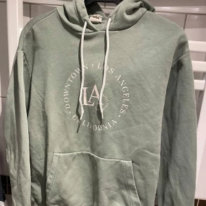 Grön hoodie med LA-tryck - Säljer en grön hoodie med tryck från Los Angeles. Storlek Small