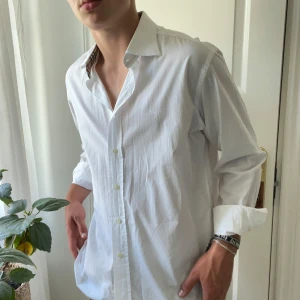Burberry skjorta vit  - Inga som helst defekter, storlek 42 vilket motsvarar ungefär L. Stor på mig som är 180,75 kg. Kom med frågor! Kanske ser ut som en missfärgning eller likande men det är bara galgen som syns igenom! 
