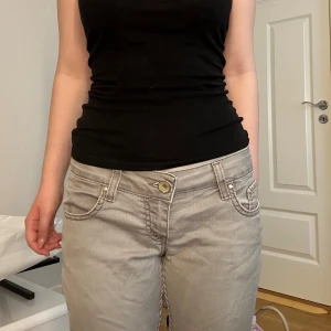 Grå jeansbyxor med broderade fickor - Säljer ett par grå jeans från Purlin Women med snygga broderade detaljer på bakfickorna. Byxorna är lågmidjade, raka ben och har snygga bakfickor. Aldrig använda men fått dom vintage och säljer för att dom tyvärr är för stora, pris går att diskuteras