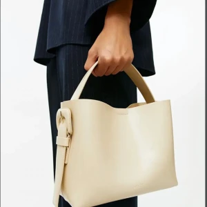 Beige väska från ARKET - Säljer en beige väska från ARKET. Väskan är använd fåtal gånger och det är mellan storleken. Köpte för 1990kr och säljer för 950.💗💗