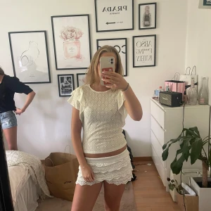 Vit blus med volangärmar och struktur - Supersöt vit blus med volangärmar och ett snyggt strukturerat mönster över hela toppen. Den har rund halsringning och är lätt figursydd. Perfekt för dig som gillar romantiska och feminina detaljer.