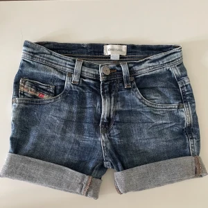 Blå jeansshorts från Diesel - Snygga blå jeansshorts från Diesel!💕 Stl: 10år Dom har klassisk femficksdesign, uppvikta benslut och slitna detaljer. Shortsen har normal passform, bälteshällor och tydliga sömmar!