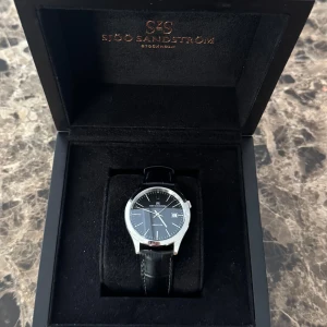 Sjöö Sandström Jubilee Steel Klocka - En Sjöö Sandström klocka i mycket gott skick då den knappt använts. Förlängd garantibevis från 2024 och följesedel/kvitto finns (obs bilder). Facetime, en video eller fler bilder går att lösa om så krävs. Två extra hål i läderarmbandet. Priset går att diskuteras. 