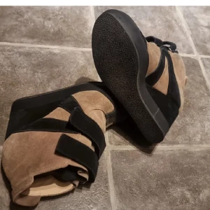 Marantstyle wedges - Snygga sneakers Marantstyle med kilklack i beige och svart mocka. Skorna har breda svarta kardborreband och en hög svart platåsula. Supersnygga och ovanliga. Storlek 36.