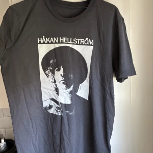 Håkan Hellström svart t-shirt Ullevi 2025 - Svart t-shirt med vit print av Håkan Hellström på framsidan och Ullevi 2025-datum på baksidan. Klassisk rund hals, kort ärm och rak passform. Perfekt merch för dig som älskar Håkan och vill sticka ut på konserten. Aldrig använd 