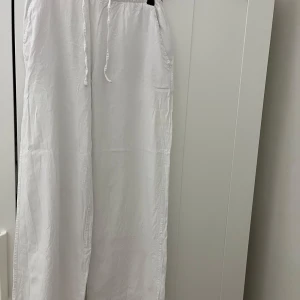 Vita linnebyxor - Luftiga vita linnebyxor från 157 i storlek XS. Byxorna har elastisk midja med snörning och raka, vida ben. Perfekta för varma dagar när du vill ha en chill och avslappnad stil. 