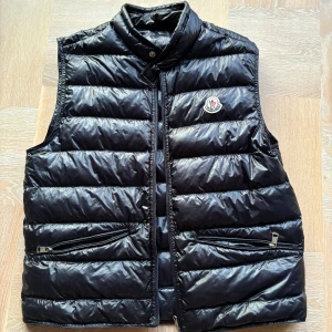 Moncler gui väst navy - Snygg navy dunväst från Moncler. Storlek 2 (s/m). Skräddar lagning på baksidan sista bilden som knappt snyns alls. Köptes från kaspersheat några som jag har slutat använda flera år sedan. Kanske kan hitta tagsen vid behov, hör av dig vid frågor eller prisförslag.