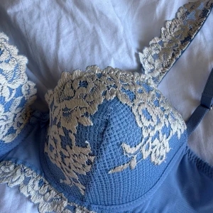 Blå spets-bh med broderade detaljer - Supersöt ljusblå bh med vackra broderade spetsdetaljer över kuporna och axelbanden. Kuporna har ett blommigt mönster och bh:n har justerbara axelband. Perfekt för dig som gillar romantiska och unika underkläder. Aldrig använd
