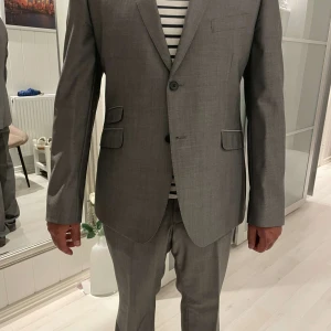 Grå kostym från Bläck, storlek 54 - Snygg grå kostym från Bläck i storlek 54. Tillverkad i en mix av 50% ull och 50% polyester för en stilren look och skön känsla. Säljs för att den är för stor för mig😊