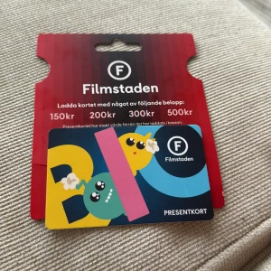 Filmstaden present kort (150) - Bilderna visar ett presentkort från Filmstaden laddat med 150 kr, perfekt för biobesök och snacks. Kortet har en färgglad och lekfull design som passar unga och filmälskare. Giltigt i 2 år från inköpsdatum och kan användas på alla Filmstadens biografer. Håller i cirka 5 månader till 
