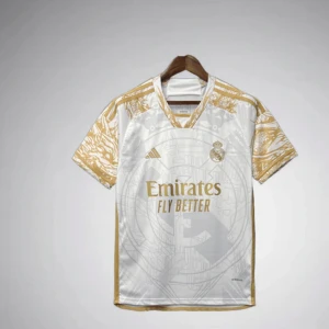 Real Madrid vit/guld matchtröja Adidas - Snygg Real Madrid fotbollströja i vitt med guldiga detaljer och mönstrade ärmar. Adidas-logga och klubbmärke på bröstet, samt Emirates Fly Better-tryck i guld. Tillverkad i lätt och ventilerande material, perfekt för match eller träning.