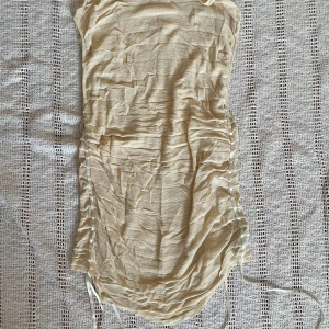 Beige blus från Zara - Supersnygg beige blus från Zara i tunn, lätt och luftig bomullsmix. Klänningen har snörning i sidorna för en cool rynkad effekt och är ärmlös med en kroppsnära passform. Perfekt för varma dagar när du vill känna dig både chill och trendig.