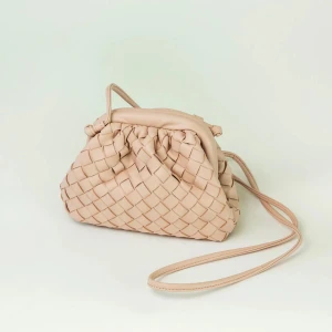 Beige flätad axelväska i skinn - Säljer en beige axelväska med snygg flätad design och lång rem. Väskan är gjord i mjukt skinn och är en super söt rosa färg. Aldrig använd lapp finns kvar!! 
