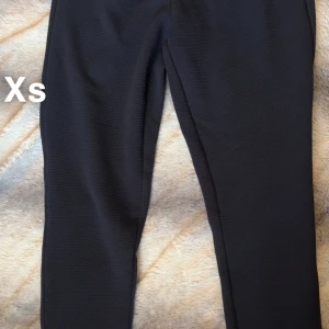 Marinblå slim byxor i XS - Marinblå byxor i slim fit med diskret struktur i tyget. Snygg och enkel modell som passar till många olika stilar. Byxorna har en klassisk rak design och är tillverkade i ett stretchigt material för extra komfort. 🌸Fint använt skick. Storlek xs