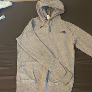 Grå hoodie från The North Face - Säljer en grå hoodie från The North Face med svart logga på bröstet och en stor grafisk ryggdetalj 