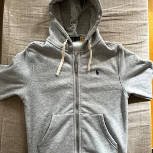 Grå hoodie från Polo Ralph Lauren - Riktigt skön ralph lauren hoodie. Tröjan är använd endast en gång. Säljer pga den är för liten. Hör av er vid frågor!