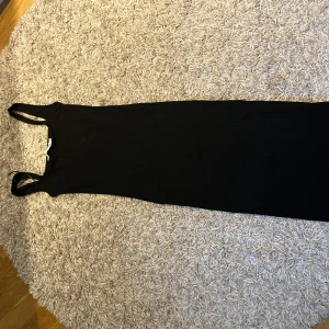 Svart ribbad långklänning från lager 157 - Säljer en svart ribbad långklänning från märket lager 157. Klänningen är ärmlös med rund halsringning och har en tight passform. Perfekt för dig som gillar en enkel och stilren look.