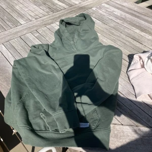 Grön hoodie från 157 - Mjuk grön hoodie från 157 med klassisk huva och dragsko. Tröjan har ribbade muddar vid ärmslut och nederkant. Perfekt för en avslappnad stil.