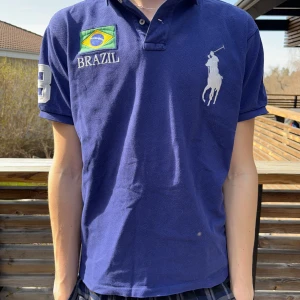 Blå pikétröja från Ralph Lauren - Säljer en blå pikétröja från Ralph Lauren som är i väldigt fint skick. Finns endast en liten skada på piken som du kan se på sista bilden. Hör av er vid funderingar 