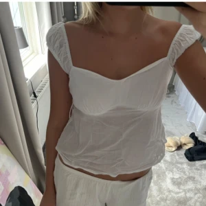Vit blus med puffärmar - Säljer en söt vit blus med puffärmar och knytband i sidan. Perfekt för sommardagar och har en romantisk stil. Blusen är lätt och luftig, vilket gör den idealisk för varma dagar.