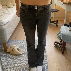 Svarta bootcut jeans - Snygga svarta bootcut jeans med låg midja och två knappar fram. Jeansen har en klassisk femficksdesign och en lätt tvättad look. Perfekta för en avslappnad stil. Midjemått: ca 37 cm men är stretchiga, innerbenslängden: ca 77cm💗