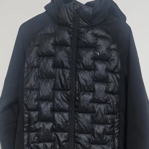 Svart pufferjacka från Everest - Säljer en svart pufferjacka från Everest med dragkedja och huva. Jackan har en quiltad design och är perfekt för kyligare väder. Den är både stilren och funktionell.