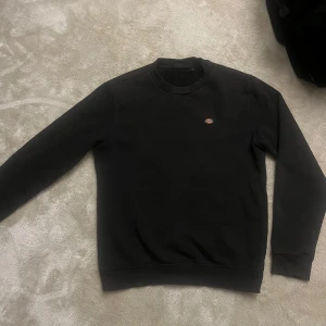 Svart sweatshirt från Dickies - Säljer en klassisk svart sweatshirt från Dickies med rund hals. Perfekt för en avslappnad stil. Den har en liten logotyp på bröstet. Sitter som S är storlek XS. 