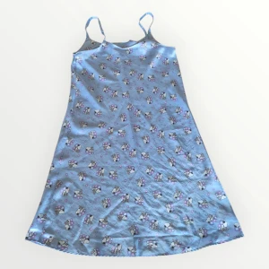 Nattlinne med Snobben på - Sött blå nattlin e med ett charmigt mönster av Snoopy och hjärtan. Klänningen har smala axelband och är perfekt för en avslappnad dag. Materialet ser ut att vara mjukt och bekvämt. Klänningen är troligen egensydd och saknar lapp och storleksmärkning. Uppskattningsvis en M eller L.