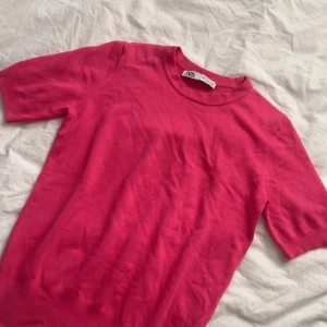 Rosa kortärmad tröja från Zara - Säljer en snygg rosa tröja från Zara med korta ärmar. Perfekt för en färgglad look. Tröjan har en enkel design och är gjord i ett mjukt material.