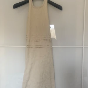 Beige ribbad klänning - Snygg beige ribbad klänning med dekorativa hålstickade detaljer. Klänningen är ärmlös och har en stilren design som passar perfekt för varmare dagar.