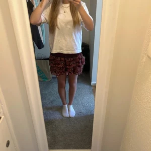 Mönstrad kortkjol med volanger - Säljer en söt kortkjol med volanger i ett färgglatt mönster. Kjolen har en bekväm passform och är perfekt för varma dagar. Den är lätt och luftig, vilket gör den idealisk för sommarens alla äventyr. Den är i strl 158/164 men passar xs och uppåt eftersom det stretchiga materialet 