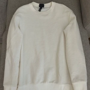 Vit ribbad tröja från H&M - Säljer en stilren vit ribbad tröja från H&M i regular fit. Tröjan har rund halsringning och långa ärmar, perfekt för en clean och enkel look. Passar till många olika outfits och är superbekväm.