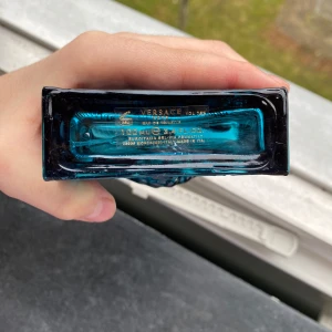 Versace Eros Eau de Toilette herrparfym 100ml - Versace Eros herrparfym i en stilren, fyrkantig blå glasflaska med guld-detaljer och klassiskt Versace-mönster. Flaskan rymmer 100 ml och kommer med originalkartong. En ikonisk doft för honom.