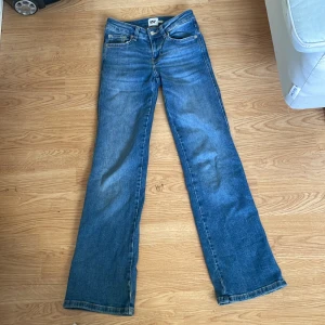 Blå bootcut jeans från 157 - Säljer ett par blå bootcut jeans från 157 i storlek XXS och längd short. Klassisk femficksmodell med normal passform och utsvängda ben. Perfekta för dig som gillar 90-talsstilen och vill ha ett par snygga jeans till garderoben.