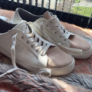 Vita sneakers  - Snygga vita sneakers med rosa mockadetaljer från Marc O’polo. Skorna har snörning och en diskret logga på sidan. Perfekta för en stilren look.