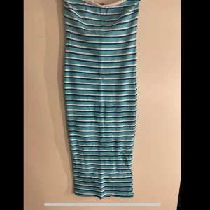 Randig tubklänning från Gina Tricot - Säljer en blå- och vitrandig tubklänning från Gina Tricot. Klänningen är axelbandslös och har en tight passform med raka linjer. Perfekt för sommardagar och enkel att styla med sneakers eller sandaler.