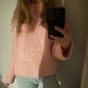 Rosa stickad tröja - Mysig ljusrosa stickad tröja med lång ärm och bred ribbad kant nedtill och vid ärmslut. Perfekt för kyligare dagar och enkel att matcha med jeans eller kjol.