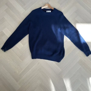 Blå ribbad tröja från Brunello Cucinelli - Säljer en stilren blå ribbad tröja från Brunello Cucinelli, tillverkad i 100% bomull. Perfekt för en avslappnad men elegant look. Tröjan har långa ärmar och en klassisk rund halsringning. Köpt på vestaire förra året. Priset kan diskuteras.