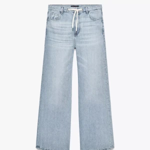 Ljusblå wide jeans med snörning - Säljer ett par ljusblå jeans med breda ben. Jeansen har en snygg snörning i midjan.Tillverkade i jeansmaterial. Ascoola jeans men inte riktigt min stil, jag är 170 och de är lite för långa för mig. Storlek 32 men skulle säga att det är 34/36. Slutsålda på Zaras hemsida
