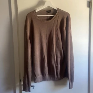 Beige stickad tröja från Rose & Born - Snygg beige stickad tröja från Rose & Born med rund hals och ribbade muddar vid ärmslut och nederkant. Tröjan har en clean look och är perfekt för dig som gillar stilrena plagg. Långärmad och i mjukt material som känns skönt mot huden.